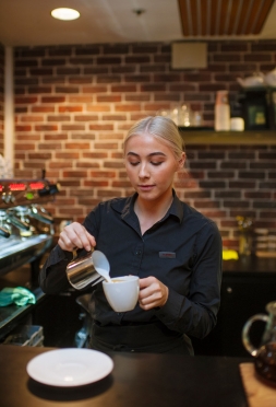 Bilde av barista som heller melk i kaffekopp