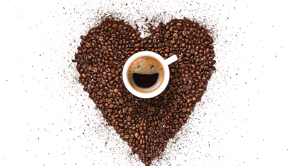 heart made from coffee beans and ground coffee on a white background. in the center is a cup, in a cup from coffee foam a happy smiling face. invigorating drink concept